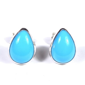 Puede incluir: Un par de pendientes de plata en forma de lágrima con piedras de color azul claro.