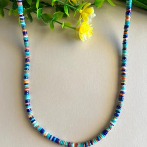May include: A turquoise, blue, and orange beaded necklace. The beads are small and round, and they are strung together in a repeating pattern.