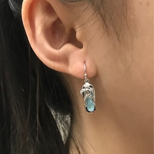 Puede incluir: Pendientes de plata con una piedra preciosa azul en forma de chancla.