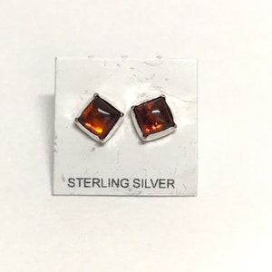 May include: A pair of sterling silver earrings with square amber stones.