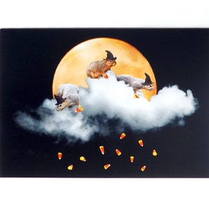May include: Three squirrels wearing witch hats fly on a cloud in front of a full moon. Candy corn falls from the cloud.