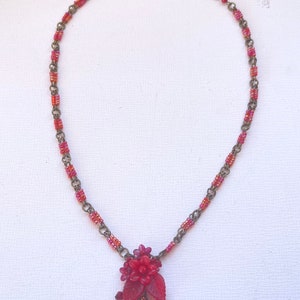 May include: A red beaded necklace with a red flower pendant and crystal accents.