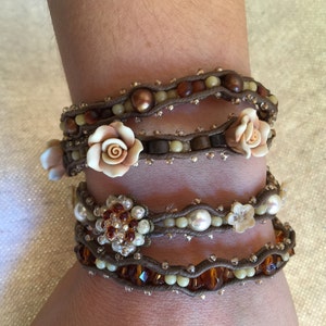 May include: Wrap bracelets with brown cord, adorned with beads in shades of brown, cream, and amber. Some bracelets feature floral accents and pearl-like beads, creating a layered, bohemian style.