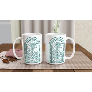 May include: Two white ceramic mugs with a teal green design. The design features a floral arch with the text "He walks with me and he talks with me and he tells me I am his own."