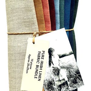May include: A bundle of ten linen fabric squares in various colours, including beige, gold, and blue, tied with twine. A tag reads "Pure Irish Linen Fabric Bundle" with a black and white photo and measurements of approximately 25x25cm.