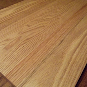 May include: A close-up of a light brown wooden cutting board with a smooth surface and visible grain patterns.