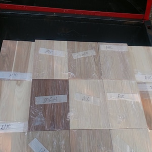 May include: A close-up of 10 wood samples, each with a handwritten label. The labels include "HIC" and "MAH". The wood samples are arranged in a grid pattern on a truck bed.