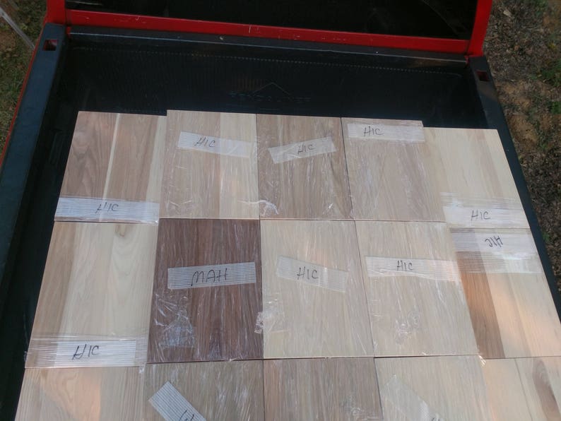 May include: A close-up of 10 wood samples, each with a handwritten label. The labels include "HIC" and "MAH". The wood samples are arranged in a grid pattern on a truck bed.