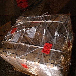May include: A large cardboard box wrapped in clear plastic and secured with white straps. The box is labeled "Fragile, Do Not Stack".