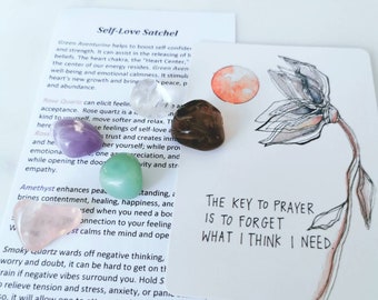 May include: A collection of tumbled gemstones in various colors, including amethyst, rose quartz, and green aventurine, arranged with a card featuring a floral illustration and the text "The key to prayer is to forget what I think I need."