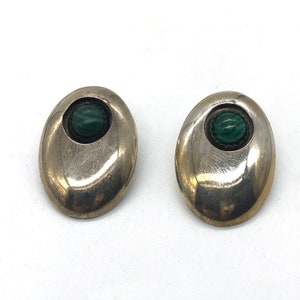May include: A pair of silver earrings with green malachite stones set in the center of each earring.
