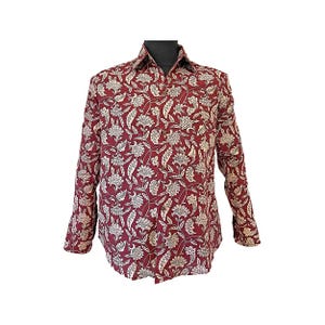 May include: A long-sleeved button-down shirt in a deep maroon colour featuring an all-over floral pattern in cream and white. The shirt has a standard collar, a front button placket with visible buttons, and long sleeves with buttoned cuffs.