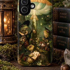 May include: A smartphone case featuring a detailed illustration of three frogs in a forest setting. One frog holds a small broom, another sits with a basket, and the third writes in a book. A large mushroom towers above them in a dark, green-toned scene.