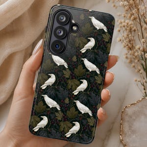 May include: A smartphone case featuring a dark, botanical pattern of deep green leaves and small dark berries. The design is populated by multiple white birds perched throughout the foliage. The case has a triple-lens camera cutout at the top left.