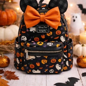Op de afbeelding: Een zwarte mini-rugzak met een herhalend Halloween-patroon van geesten, schedels en pompoenen. De tas heeft twee ronde oren, een grote oranje strik en een metalen Disney Parks Loungefly-logoplaat aan de voorzijde met een vak met ritssluiting.