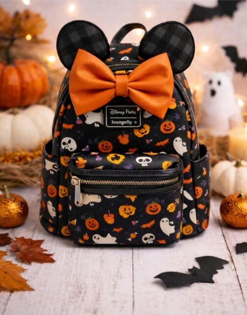 Op de afbeelding: Een zwarte mini-rugzak met een herhalend Halloween-patroon van geesten, schedels en pompoenen. De tas heeft twee ronde oren, een grote oranje strik en een metalen Disney Parks Loungefly-logoplaat aan de voorzijde met een vak met ritssluiting.
