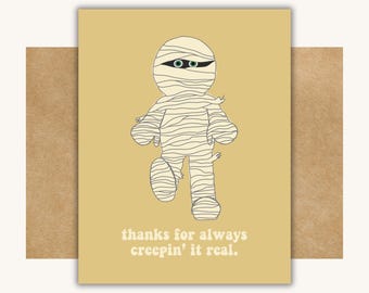May include: A yellow card with a cartoon mummy illustration and the text "thanks for always creepin' it real."