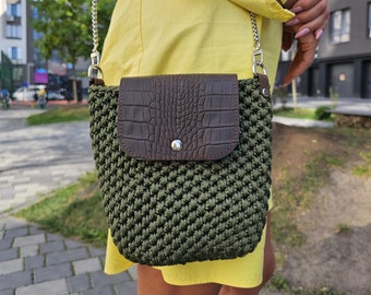 May include: A green crocheted crossbody bag with a brown leather flap and a silver chain strap.