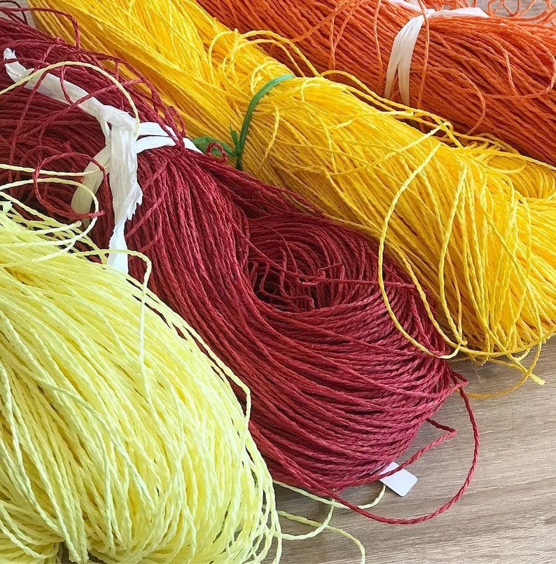 May include: Four spools of colorful string, yellow, orange, red, and light yellow. The spools are arranged in a row, with the yellow spool at the top and the light yellow spool at the bottom.