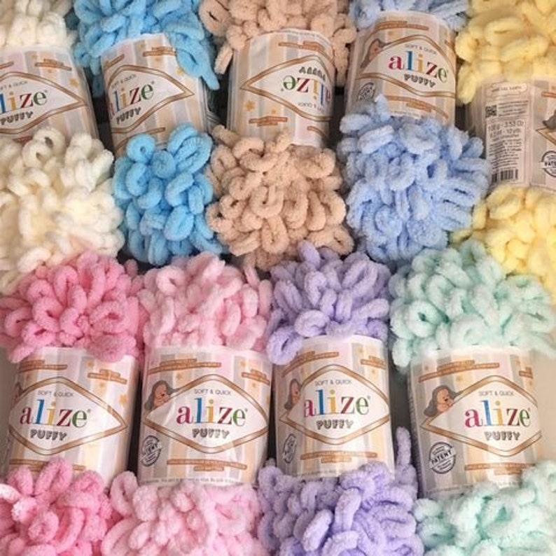Pu&ograve; includere: Assortimento di gomitoli di lana colorati in diverse tonalit&agrave; pastello, tra cui rosa, blu, giallo e verde. Ogni gomitolo &egrave; etichettato "Alize Puffy" e presenta una texture morbida e soffice.