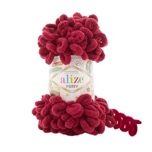 Pu&ograve; includere: Un gomitolo di filato Alize Puffy di colore rosso bordeaux scuro. Il filato &egrave; composto da fibre morbide e soffici, ideale per creare progetti accoglienti e confortevoli. L'etichetta sul gomitolo riporta "Alize Puffy" e "No Needles No Hooks Collection".