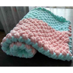 Pu&ograve; includere: Una morbida coperta per neonati in rosa e azzurro. La coperta &egrave; realizzata con un filato spesso e ha una trama intrecciata.
