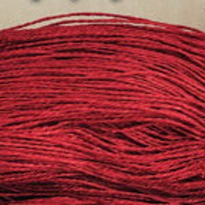 May include: A large spool of deep red yarn, tied with a brown string.