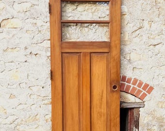Puede incluir: Una puerta rectangular de madera con acabado marrón medio, que presenta un panel de vidrio en la parte superior dividido por un travesaño horizontal y dos paneles verticales empotrados en la sección inferior, con un orificio circular.