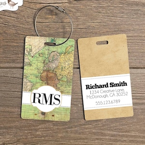 May include: A luggage tag with a vintage world map design. The tag has a brown background with a white circle in the center that says "RMS". The tag also has a brown paper tag attached to it with the text "Richard Smith, 1234 Creative Lane, McDonough, GA 30252, 555.123.6789".