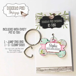 May include: A bone-shaped pet ID tag with a floral design, the name "Sophie" and a phone number. Includes a jump ring and a C-clamp bale for attaching to a pet collar. The tag is from Doodle Pad Designs.
