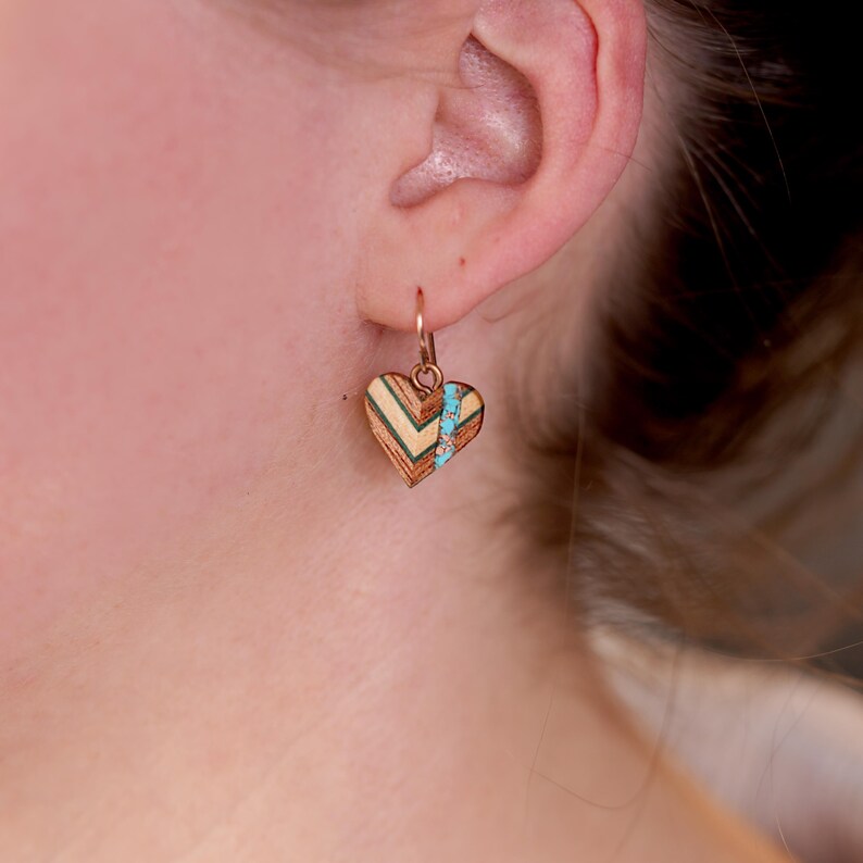 May include: A pair of heart-shaped earrings with a geometric wood pattern and turquoise accents.