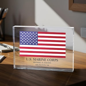 May include: A clear acrylic block with a printed image of the American flag and the text "U.S. MARINE CORPS", "MICHAEL A. COLSON", and "ARLINGTON, VA".