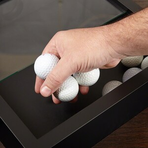 Man putting golf balls in the golf ball holder.