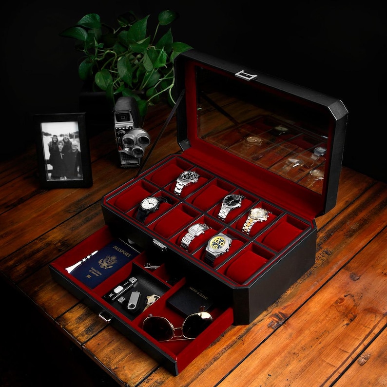 Puede incluir: Caja de reloj de cuero negro con interior de terciopelo rojo. La caja tiene una tapa de vidrio y un caj&oacute;n extra&iacute;ble. El caj&oacute;n est&aacute; forrado de terciopelo rojo y contiene un pasaporte, llaves y gafas de sol.
