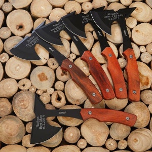 May include: Five black and red personalized tomahawk axes with wooden handles. The axes are engraved with names and dates. The axes are arranged on a background of stacked wooden rounds.