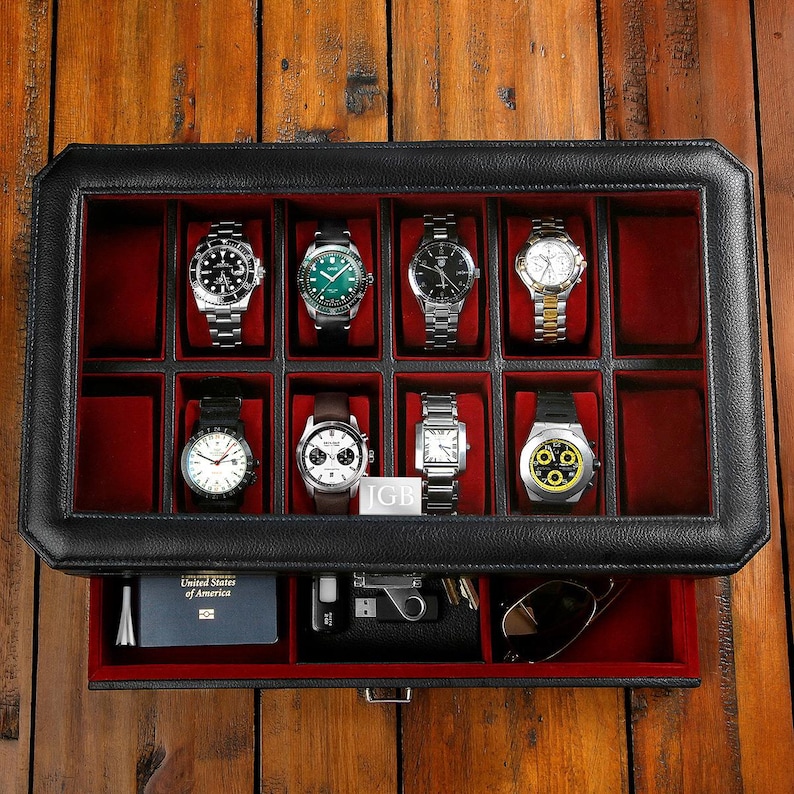 Puede incluir: Caja de reloj de cuero negro con tapa de vidrio e interior de terciopelo rojo. La caja tiene un caj&oacute;n con interior de terciopelo rojo. La caja est&aacute; llena de ocho relojes.