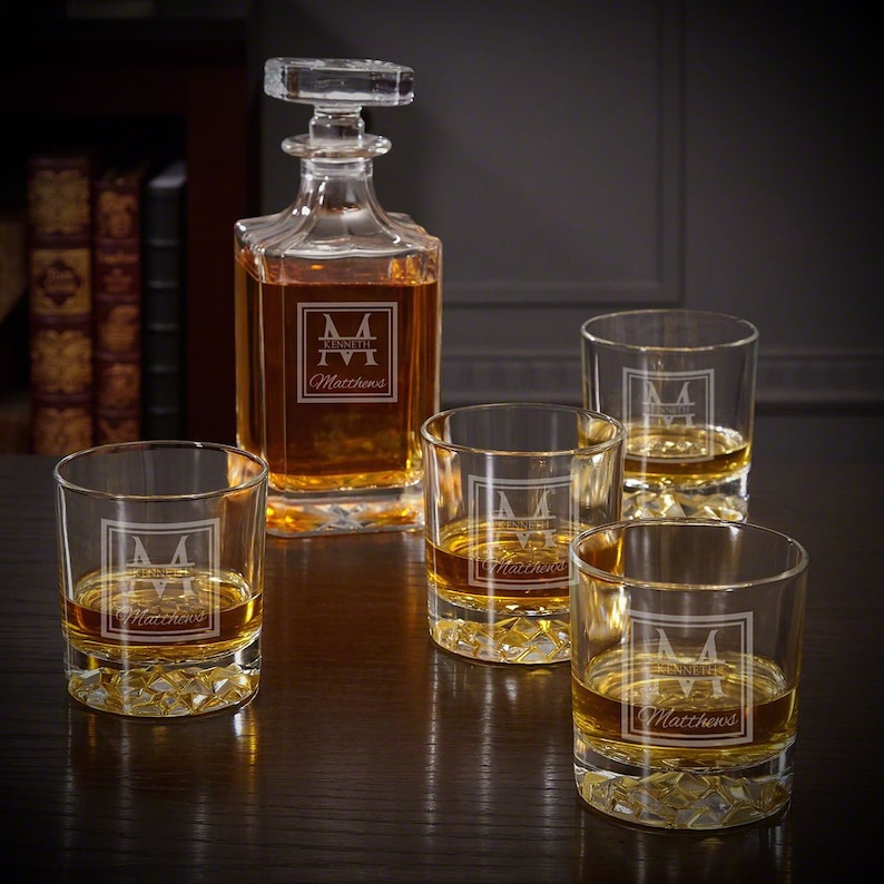 May include: A set of four clear glass whiskey glasses and a matching decanter, all engraved with the monogram "M" and the name "Kenneth Matthews".