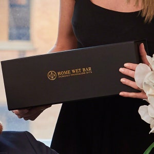 Pu&ograve; includere: Una scatola regalo nera con scritta dorata "HOME WET BAR INCREDIBLE PERSONALIZED GIFTS".