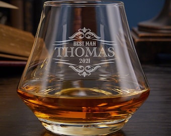 May include: A clear glass whiskey tumbler with a wide base and a flared top. The glass is engraved with the text "Best Man Thomas 2021" and a decorative design.