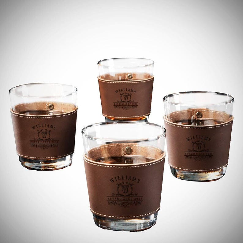 May include: Four brown leather wrapped whiskey glasses with the text "Williams Established 2002" engraved on the leather.