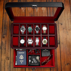 Puede incluir: Caja de reloj de cuero negro con tapa de vidrio e interior de terciopelo rojo. La caja tiene 12 compartimentos para relojes y un caj&oacute;n con un pasaporte, llaves y otros art&iacute;culos peque&ntilde;os.