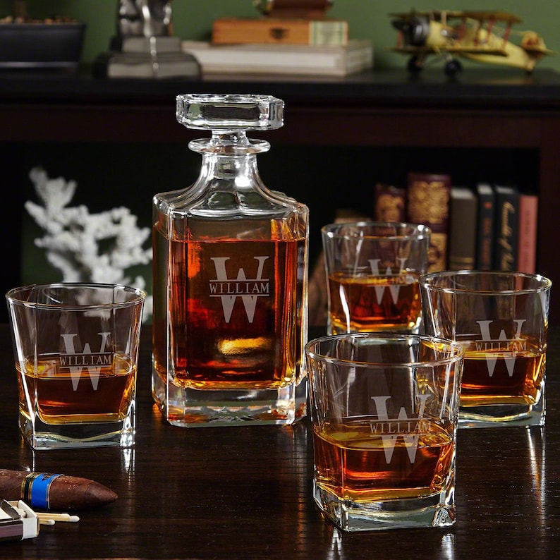 May include: A personalised decanter and four whisky glasses with the name "William" etched on each piece. The decanter is filled with amber liquid and the glasses are filled with a clear liquid.