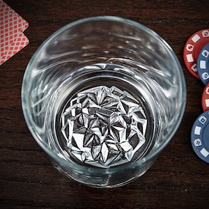 May include: A clear glass tumbler with a silver, geometric ice cube inside. The ice cube is made of many small, triangular pieces that fit together to form a sphere.