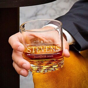 May include: A clear glass with a textured bottom, filled with amber liquid. The glass is engraved with "MR. & MRS. STEVENS" and "MARCH 13, 2025".
