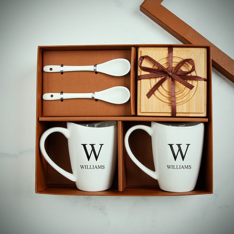 Two custom coffee mugs, two mixing spoons, and two coasters all stored inside a box.