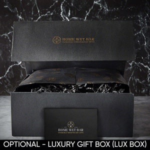 Pu&ograve; includere: Una scatola regalo nera con un logo dorato che dice "Home Wet Bar - Incredible Personalized Gifts". La scatola &egrave; aperta e piena di carta velina nera e carta triturata.