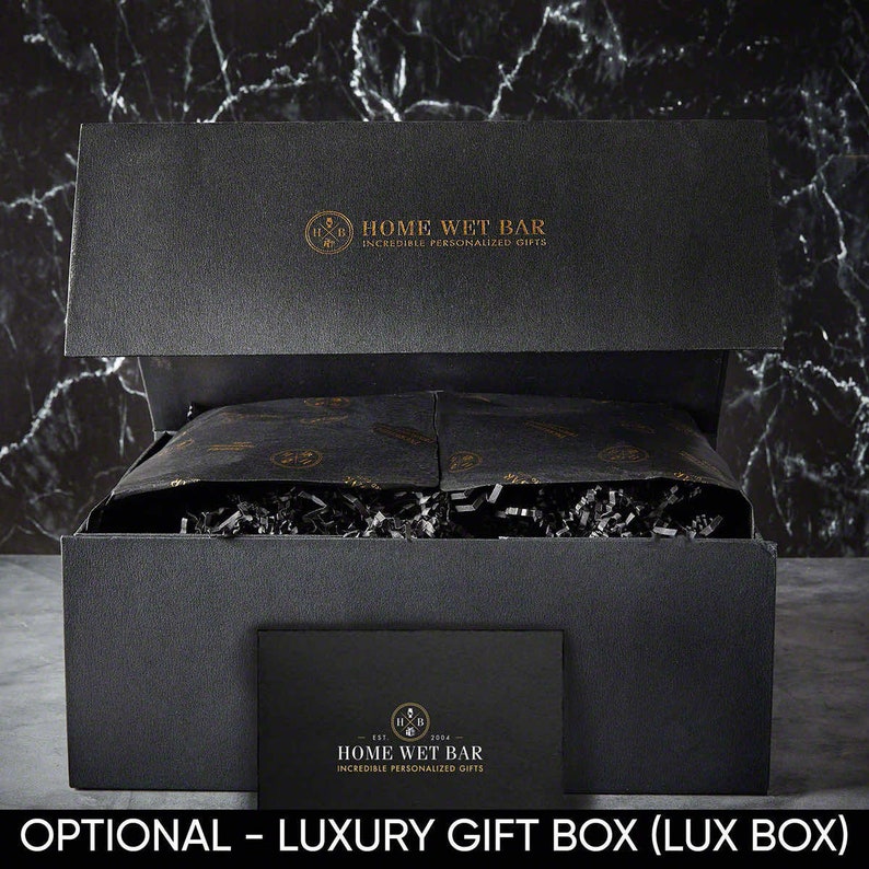 Pu&ograve; includere: Una scatola regalo nera con un logo dorato che dice "Home Wet Bar - Incredible Personalized Gifts". La scatola &egrave; aperta e piena di carta velina nera e carta triturata.