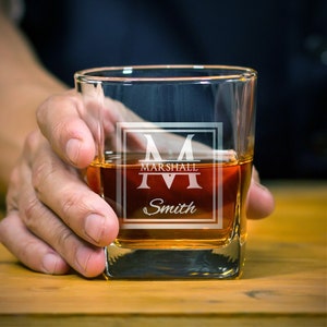 May include: A square, clear glass with a personalised design. The design features a large letter "M" with the name "Marshall" and "Smith" below it.