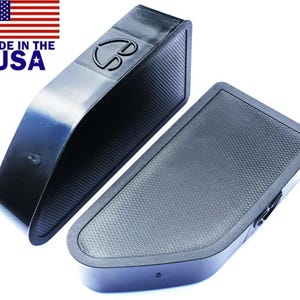 Könnte beinhalten: Zwei schwarze, abgewinkelte, rechteckige Objekte mit strukturierten Oberflächen. Ein Objekt hat eine gewölbte Oberseite und ein Logo. Das andere Objekt ist flach. Die amerikanische Flagge und der Text "MADE IN THE USA" befinden sich in der oberen linken Ecke.