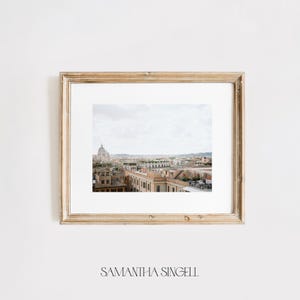 May include: A framed photograph of a cityscape with a large dome building in the distance. The buildings are a light brown color and the sky is a light blue.